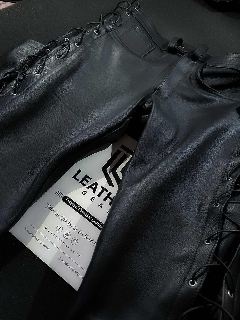 Flat front view of leather pants with visible side lacing and detailed fly, designed for gay leathermen and motorcycle fetish outfits.
