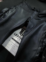 Lade das Bild in den Galerie-Viewer, Flat front view of leather pants with visible side lacing and detailed fly, designed for gay leathermen and motorcycle fetish outfits.
