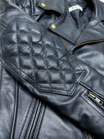 Load image into Gallery viewer, Close-up of a black leather jacket with quilted design and zipper details.
