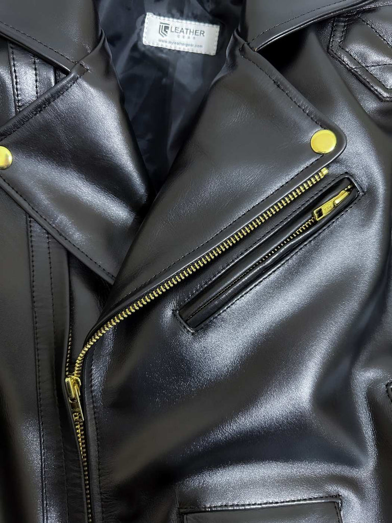 Close-up of a black leather jacket with gold zippers and buttons.