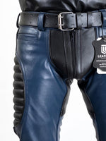 Charger l'image dans la galerie, Close-up of blue leather pants with a belt and visible brand tag on a white background
