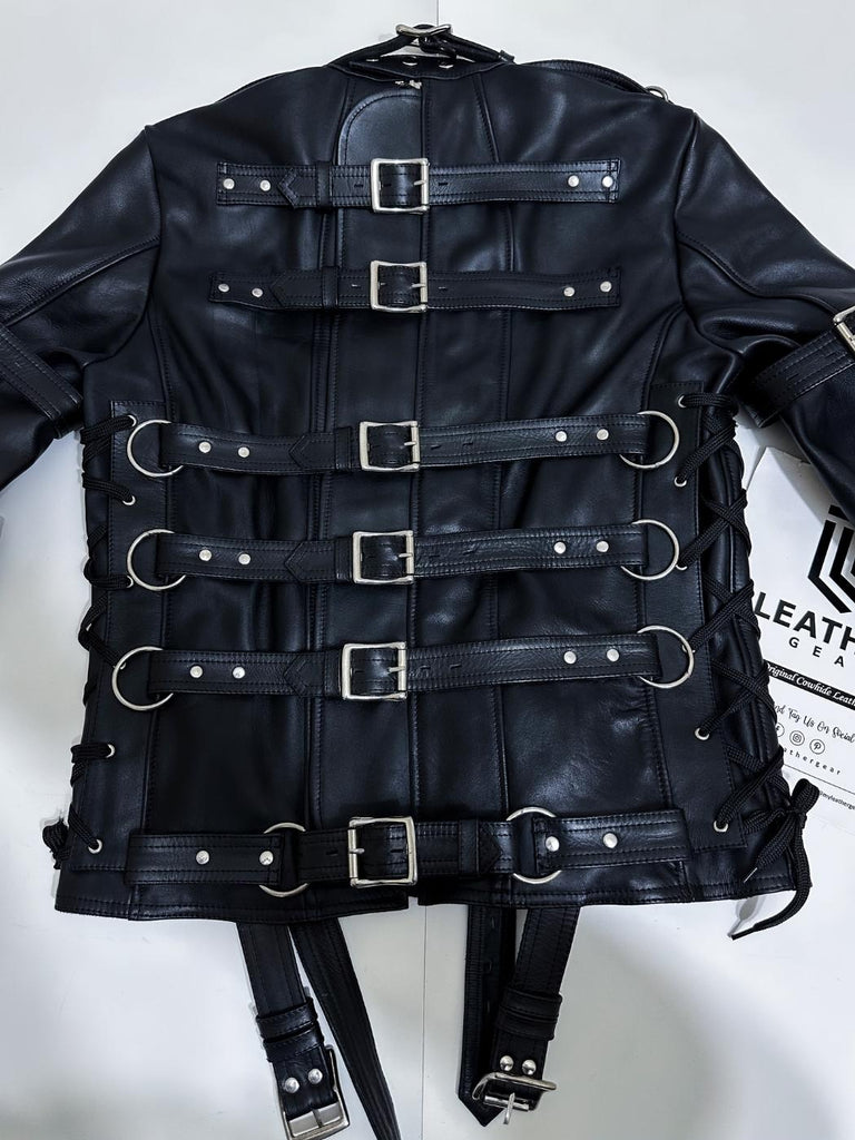 Black leather straitjacket with multiple buckles on back laying flat 