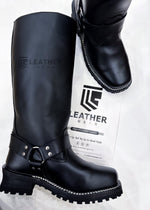 Lade das Bild in den Galerie-Viewer, Angled flat lay of Double Strap Black Leather Harness Boots showing full leather construction and Vibram lug soles for gay leather gear lovers
