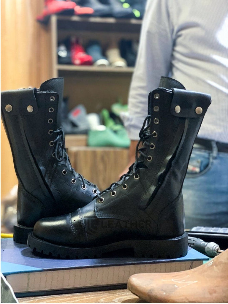 Black leather boots by leather gear on a table with a background of shoes and shelves.