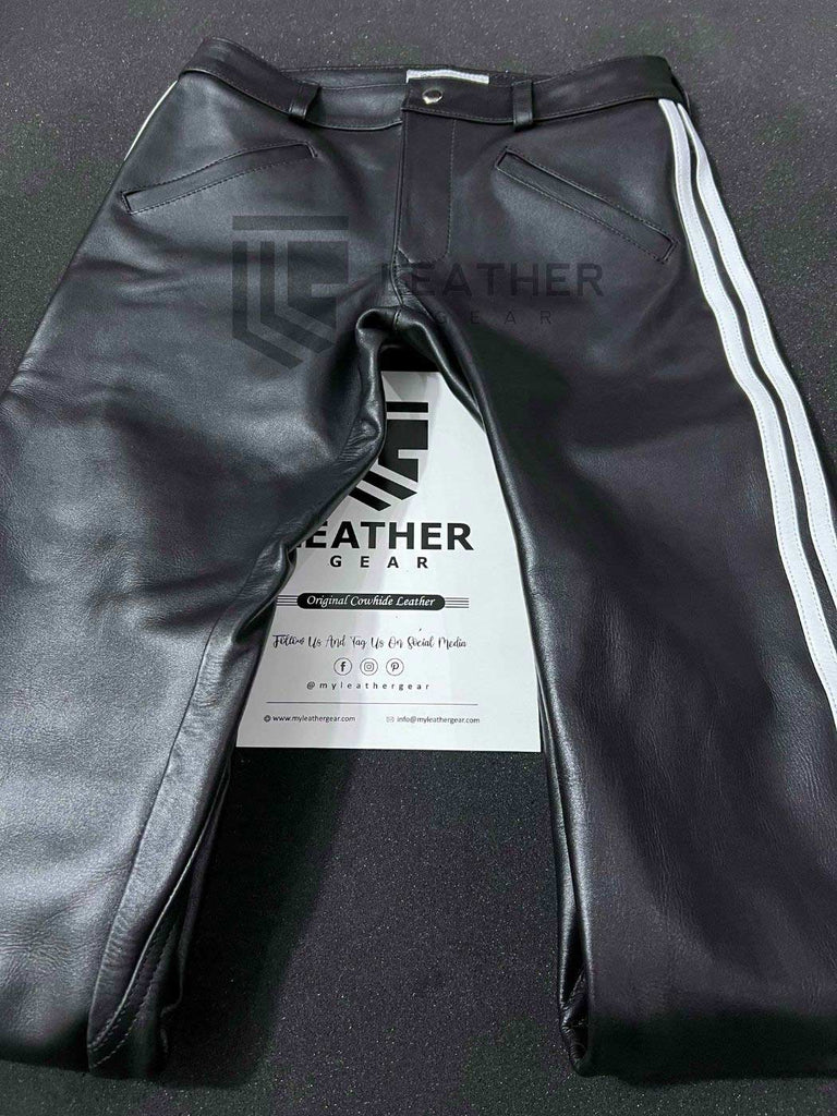 Flat lay of front side – black leather pants with bold white stripes and double zip fly